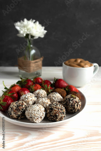 energy balls or prothin balls, healthy sweets on a flat plate with strawberries and dalgona coffee- Korean drink, trend 2020, healthy breakfast concept