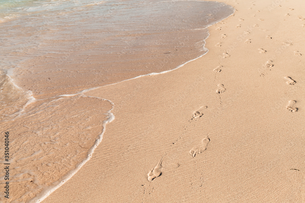 Footprints of bare feet and seawater are on a wet sand Footprints of bare feet and seawater are on a wet sand