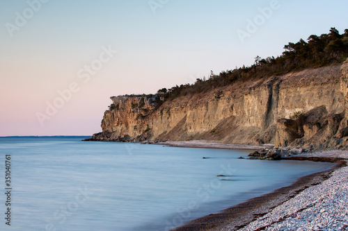 Stone beach with limestone cliff in background, Sweden
