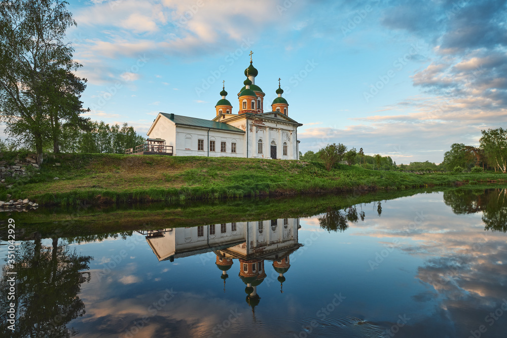 Summer landscape with the Orthodox Church and the reflection of clouds in the water of the river.