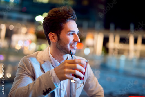 Man holding a drink at a night club outdoor photo