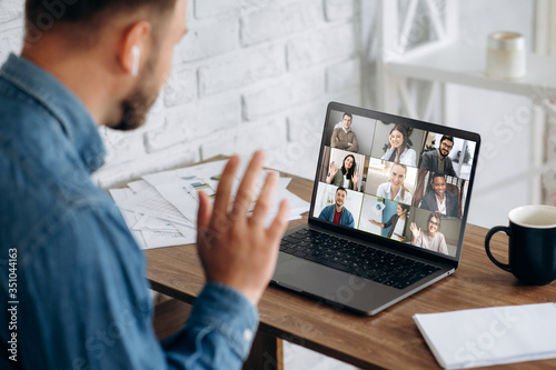 Video conference. Business partners communicate via video conference using laptop. The guy talks with his business partners appearance about plans and strategy. Distant work photo