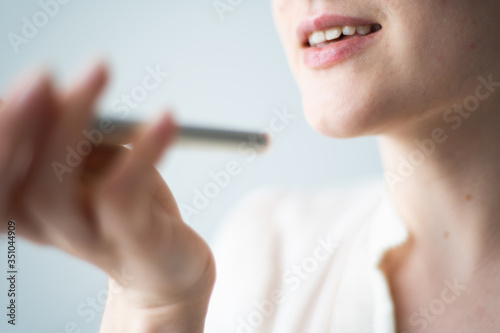 Close-up voice control of a smart home on a mobile phone. Talking mouth in the speaker of a young woman