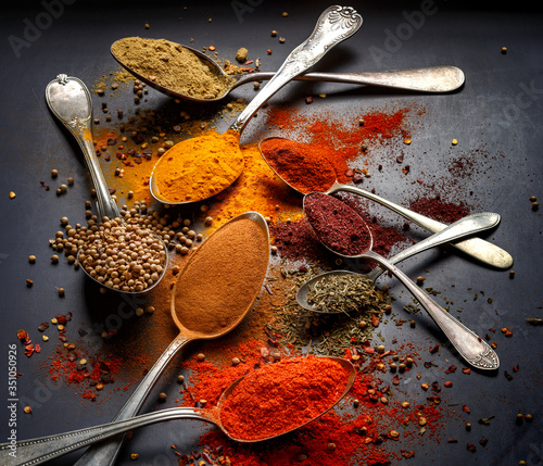 Fototapeta Naklejka Na Ścianę i Meble -  Various spices and herbs on spoons on a black background, close up