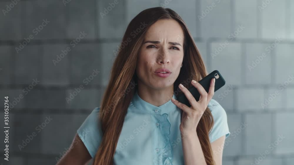 Displeased businesswoman recording voice message on cellphone in city Displeased businesswoman recording voice message on cellphone in city