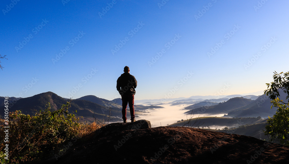 man with panoramic view of mountains and sunrise
