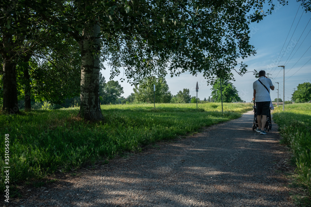 Fototapeta premium Giardino cittadino urbano parco rilassamento con cielo azzurro, passeggiata con carrozzina e telefono