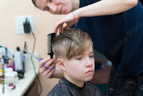 Mom cuts the hair of her son at home during quarantine amid COVID-19 coronavirus pandemic