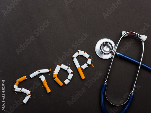 31 May of World No Tobacco Day, no smoking close up word STOP spelled text of the pile cigarette or tobacco and doctor stethoscope on black background with copy space, and Warning lung health concept