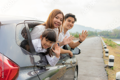 Happy Asian family with father, mother and daughter in compact car are smiling and bye bye when driving for travel on vacation. Car insurance or rental and family happy to journey concept.