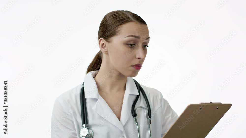 Portrait of female caucasian doctor in wihite coat, stethoscope, tablet with tests result, reading patient report. Looks surprised and doubts, touches his chin and ponders. Bad medical tests concept Portrait of female caucasian doctor in wihite coat, stethoscope, tablet with tests result, reading patient report. Looks surprised and doubts, touches his chin and ponders. Bad medical tests concept