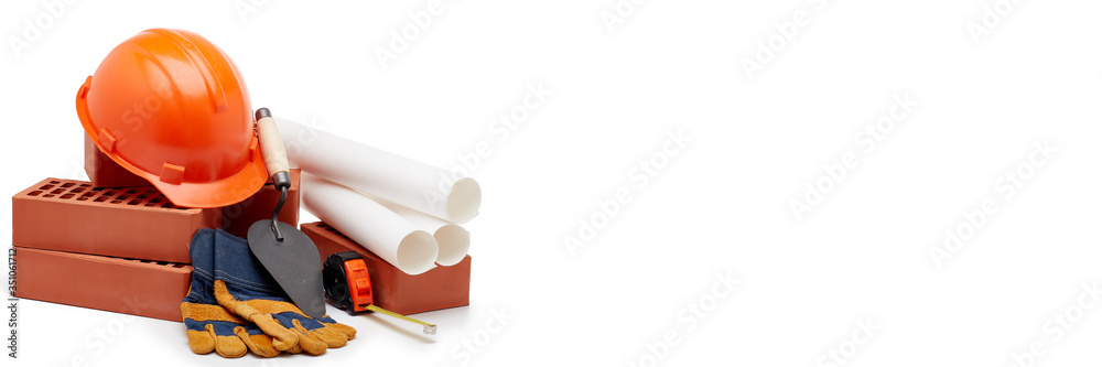 Fototapeta premium Architectural blueprints, stack of bricks, masonry trowel, construction hard hat on white background. Construction concept.