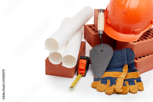 Architectural blueprints, stack of bricks, masonry trowel, construction hard hat on white background. Construction concept.
