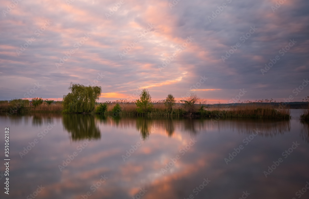 Fototapeta premium Long exposure sunset view on Ivano-Frankove (Yaniv), Yanivskyi Stav Lake and forest. Roztochia Biosphere Reserve, Lviv district, Ukraine. May 2020
