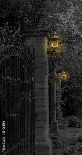 Forged fence and pillars of brick. Metal fence, building fencing. Black and white photography.
