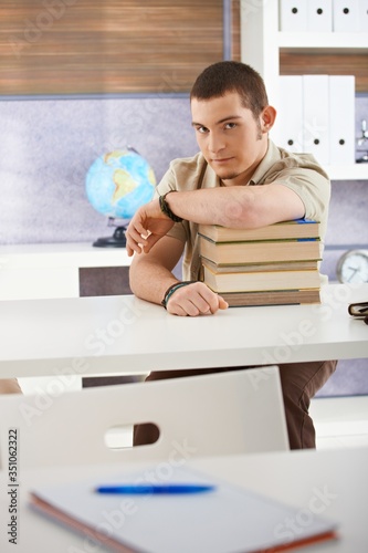 Portrait of confident student boy in classroom looking at camera.