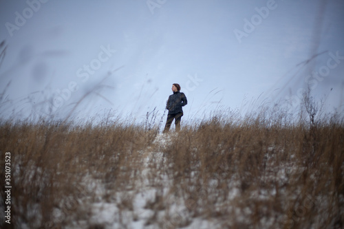 A girl stands in a field in winter. © Олег Копьёв