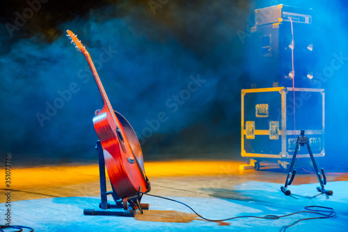 Acoustic guitar on a stand on empty stage before the concert