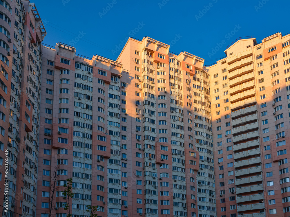 Residential facade of a high-rise building with many windows and balconies in the blue sky. Copy space