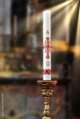 Paschal candle (Osterkerze) 2020 on the altar. Blurred background with sun rays photo