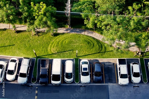 Grass on playground and Parking space, parking slot, Aerial view of cars of different type parked in the parking lot in front of grass in playground. Top view from the building.