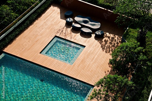 Sofa and table set with big tree outdoor around public zone at the swimming pool in hotel and resort, Holiday Vacation concept