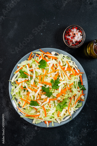 White cabbage salad coleslaw with carrot on grey kitchen table background. Top view, copy space