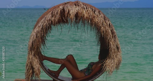girl launging at the tropical beach under the shade with a ship photo