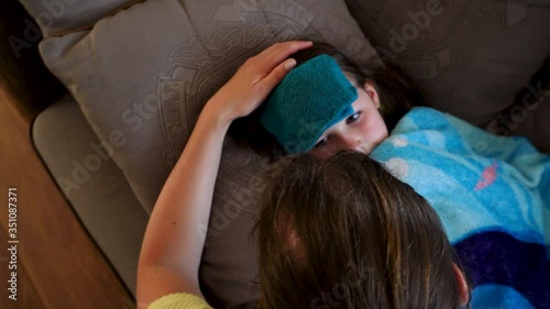 Mother nourshing sick child under a blanket and with a wet towel on the face photo