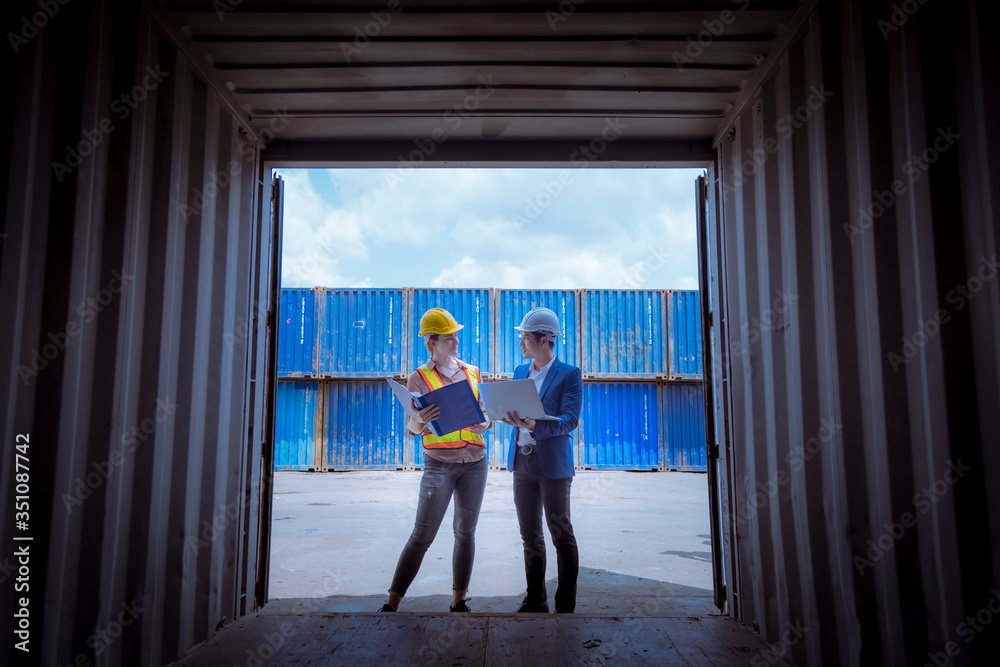 A Manager and dock worker under discussion about dock container shipping warehouse document,they wearing safety uniform hard hat and hold radio communication. A Manager and dock worker under discussion about dock container shipping warehouse document,they wearing safety uniform hard hat and hold radio communication.