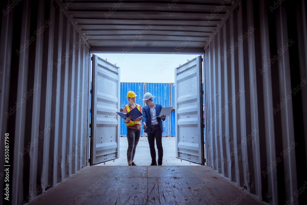 A Manager and dock worker under discussion about dock container shipping warehouse document,they wearing safety uniform hard hat and hold radio communication. A Manager and dock worker under discussion about dock container shipping warehouse document,they wearing safety uniform hard hat and hold radio communication.