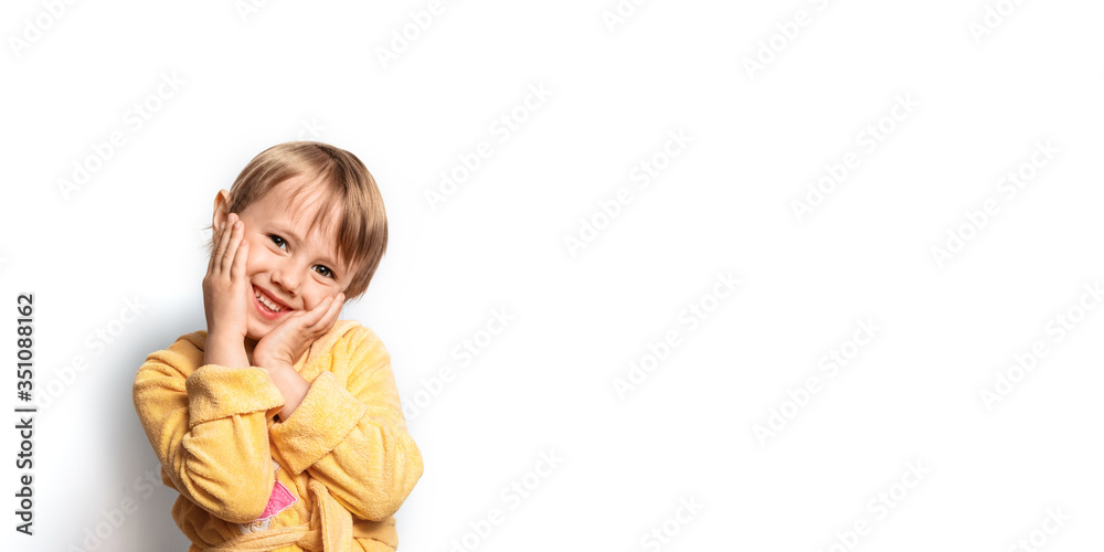 Little cute girl in a yellow bathrobe posing funny on a white background. Smile