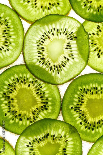 Macro shot of backlit kiwi fruit slices on white background. Top view layout