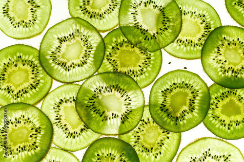 Backlit kiwi fruit slices on white background. Top view texture