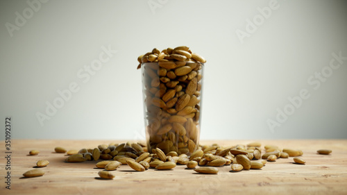 Almonds in a Cup on Wooden Floor. Nuts Overfill Glass Mug