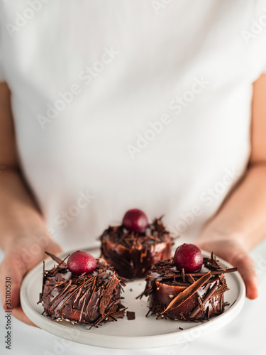 Woman holds three mini black forest cakes photo