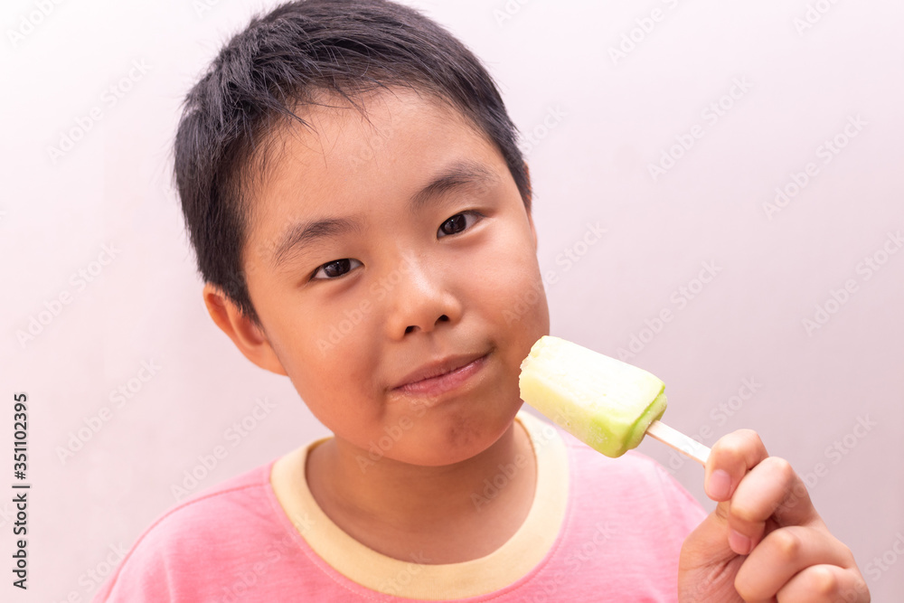 Asian boy eating a colorful frozen popsicle in the summer Asian boy eating a colorful frozen popsicle in the summer