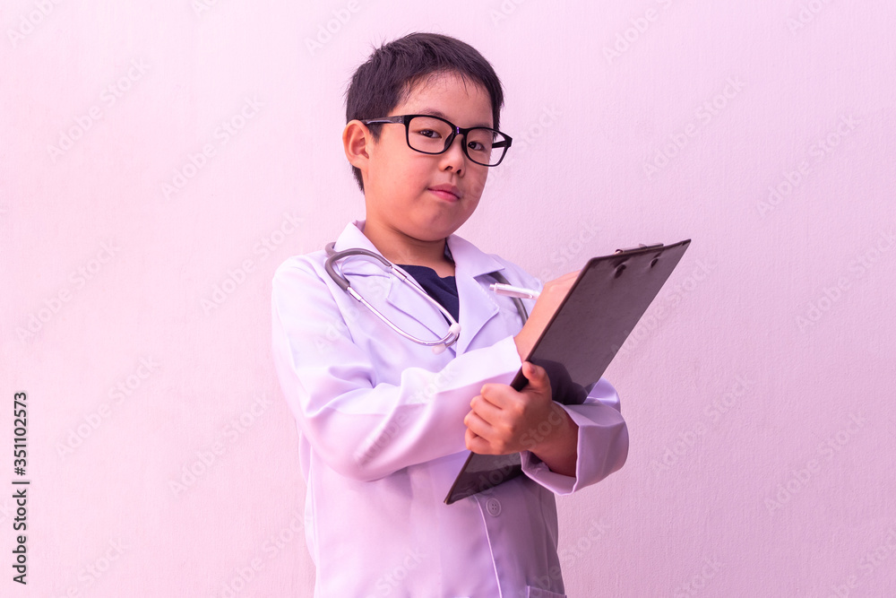 Asian boy playing doctor with stethoscope in hands and writing on clipboard Asian boy playing doctor with stethoscope in hands and writing on clipboard