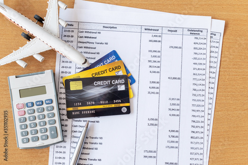 Airplane model and calculator on Bank statement and credit card on a Wooden table. Finance about Travel concept
