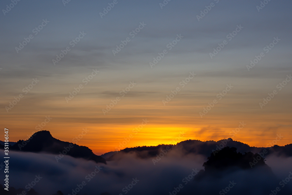 Sunrise and morning light behind the mountains with the mist covered.