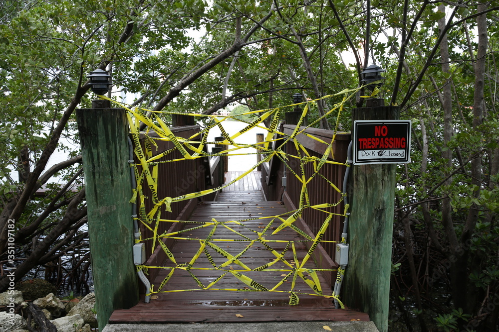 Fototapeta premium yacht pier or bridge is closed to visitors with yellow tape. The plate with the inscription but the trespassing. Covid-2019
