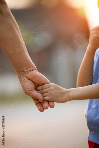 parent holds the hand of a small child