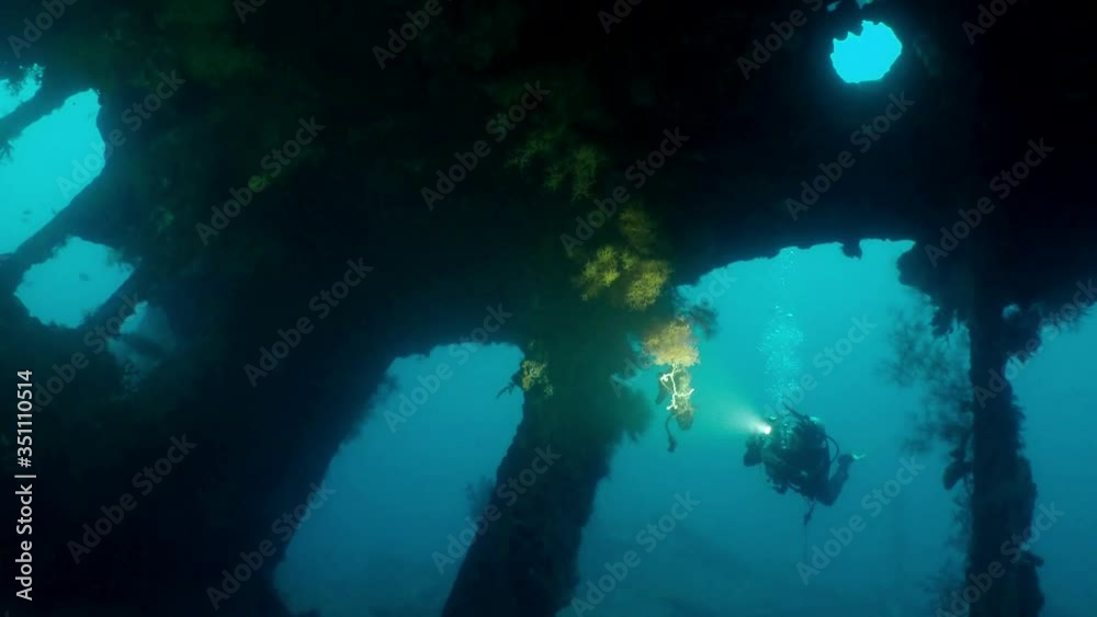 A divier exploring and filming a colorful coral reef in crystal clear water