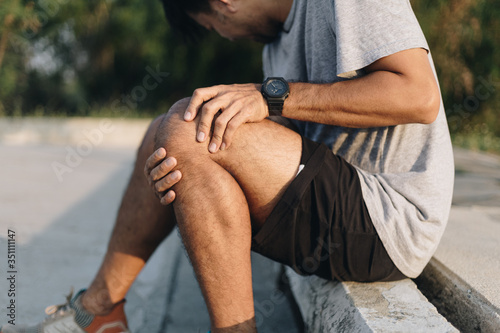 Sport man having knee ache after running and exercise, Injury from workout concept