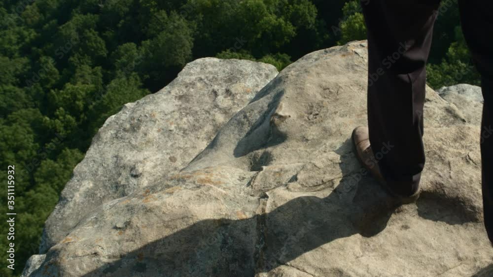 Business man approaches the edge of a cliff in slow motion, with trees a long way below. Business man approaches the edge of a cliff in slow motion, with trees a long way below.