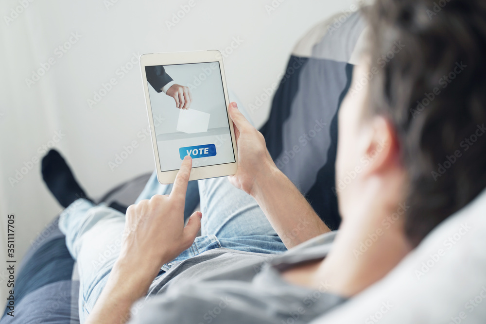 Man Voting Online Lying on Sofa Using Digital Tablet. Man Voting Online Lying on Sofa Using Digital Tablet.
