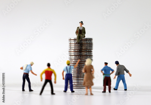 Many miniature people gathered in front of entrepreneur sitting on piles of coins.
 photo