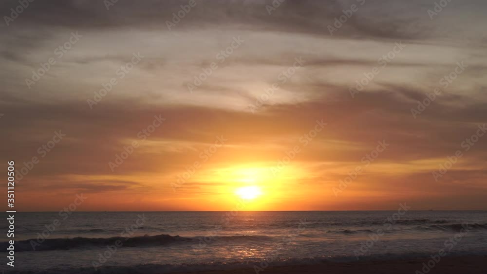 Natural videos and scenery the scene of the waves in the sea moving towards the coast, with the sun falling with gold reflected in the water At the Andaman Sea in Phuket 4K Resolution wide angle shot.