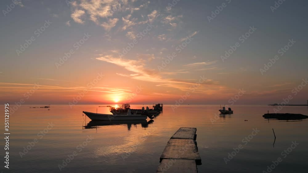 Concrete bridge on calm water with boats floating with beautiful colorful reflection twilight sunrise from sky and fisherman boat moving on water background, Bahrain. Concrete bridge on calm water with boats floating with beautiful colorful reflection twilight sunrise from sky and fisherman boat moving on water background, Bahrain.