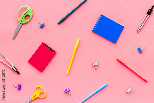 Flat lay stationery set - notebook, pen, sciccors - on pink background top view